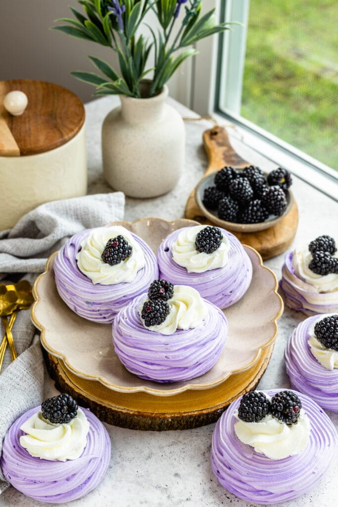 blackberry pavlovas, purple pavlovas topped with whipped cream and blackberries.
