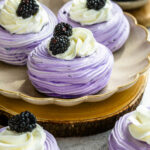 blackberry pavlovas, purple pavlovas topped with whipped cream and blackberries.