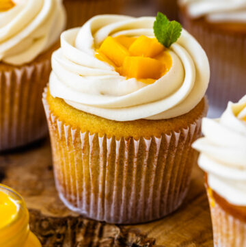 mango cupcakes with mango pieces on top and a leaf of mint.