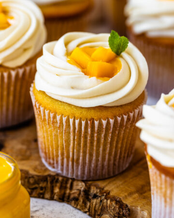 mango cupcakes with mango pieces on top and a leaf of mint.