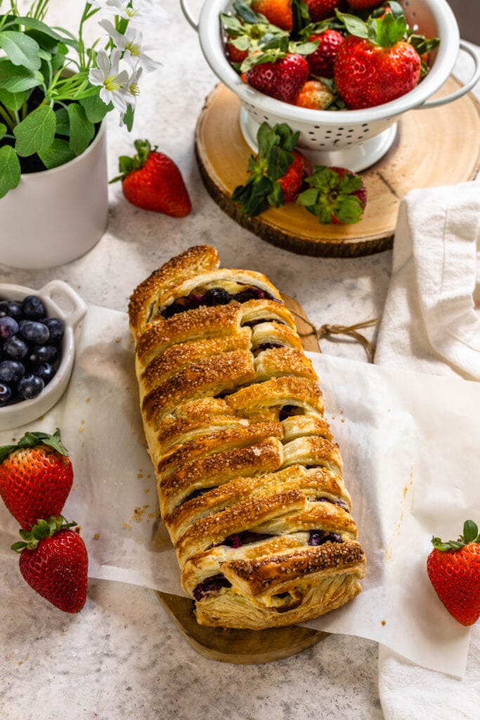 blueberry puff pastry baked and displayed next to fruits and berries.