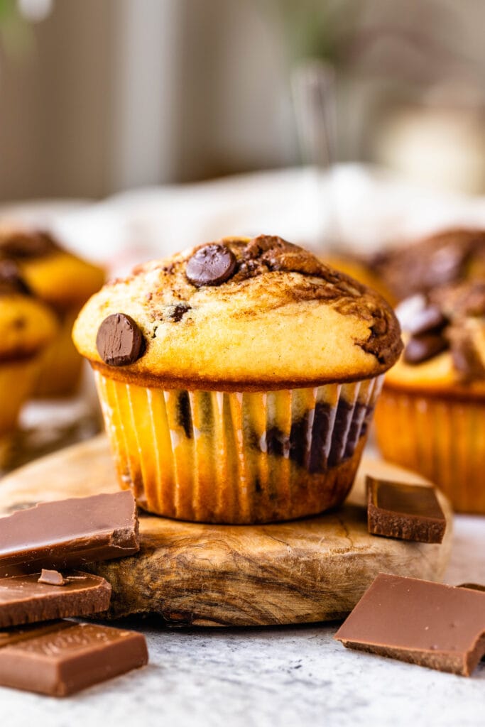 nutella muffins on top of a table with chocolate pieces around.