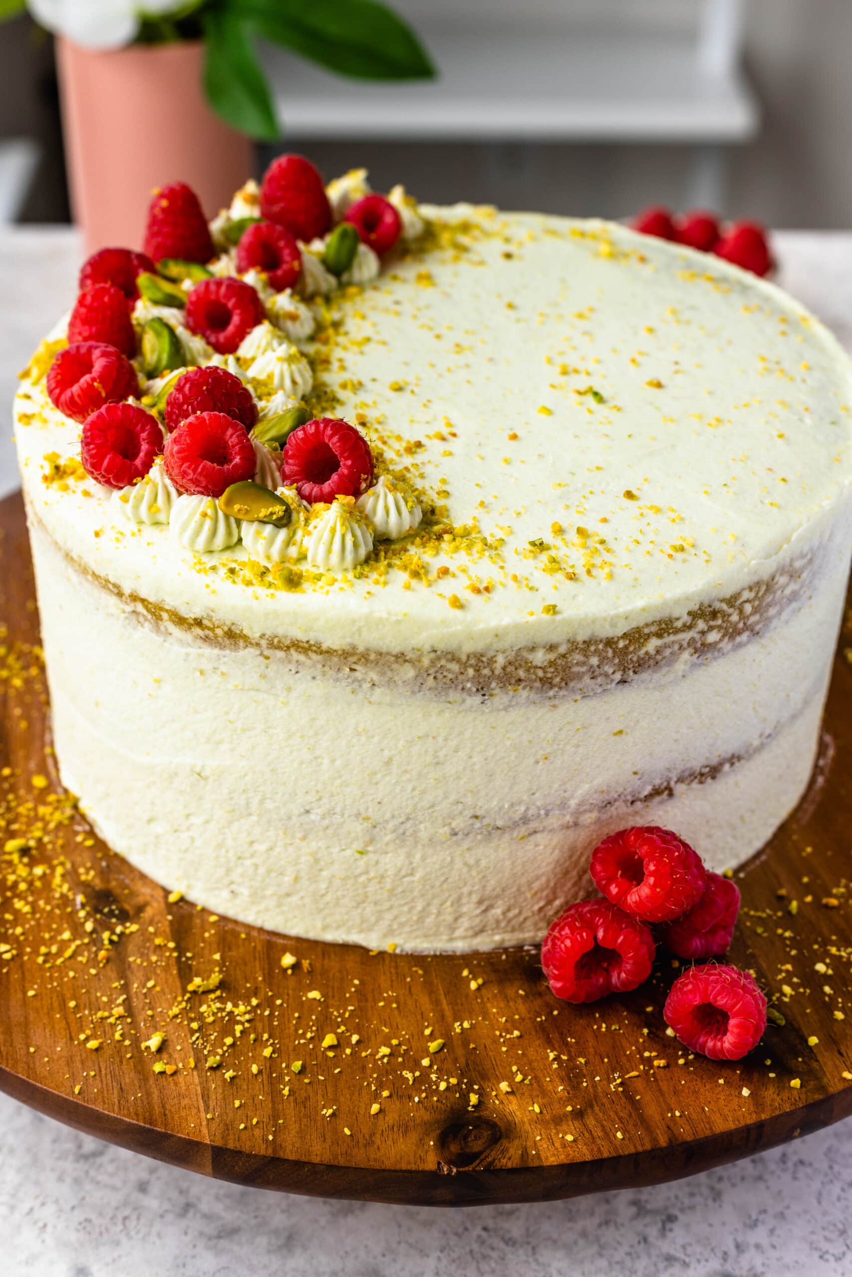 pistachio cake topped with pistachios and raspberries.