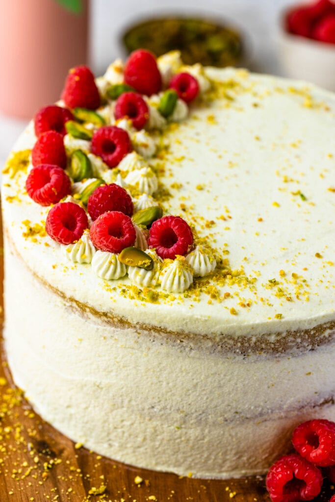 pistachio cake topped with pistachios and raspberries.