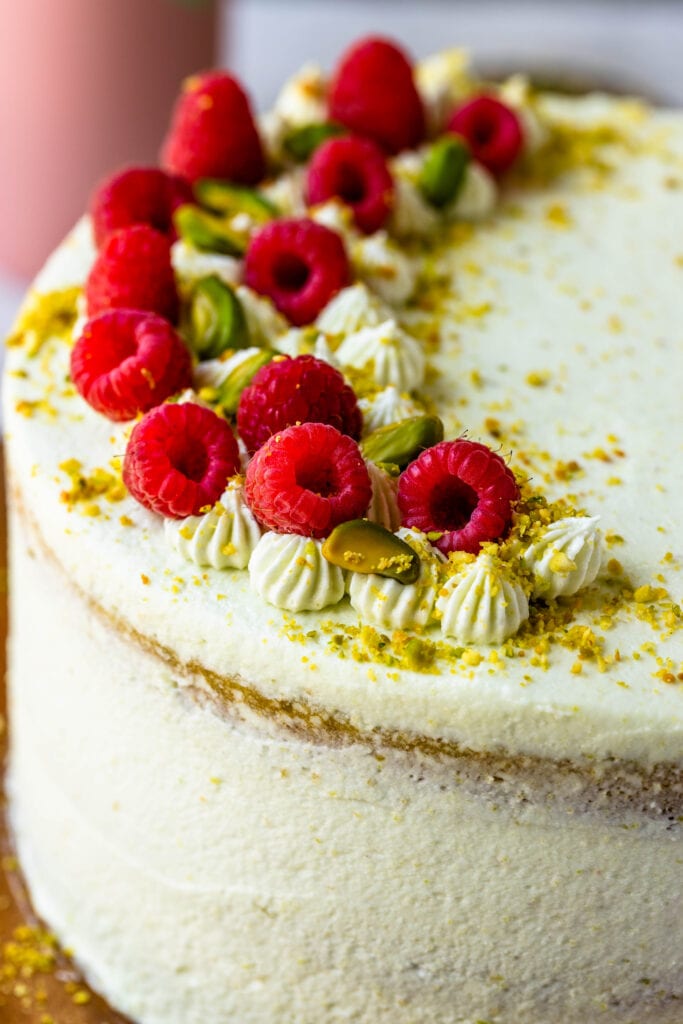 pistachio cake topped with pistachios and raspberries.