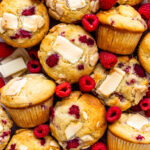 raspberry and white chocolate muffins topped with white chocolate and raspberries.