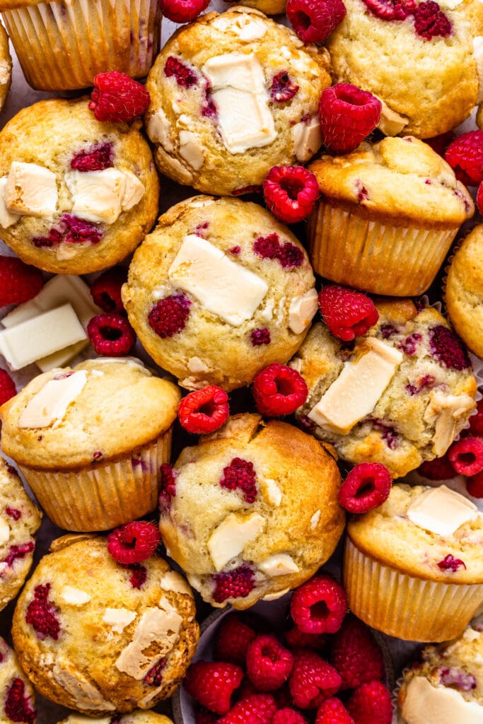 raspberry and white chocolate muffins topped with white chocolate and raspberries.