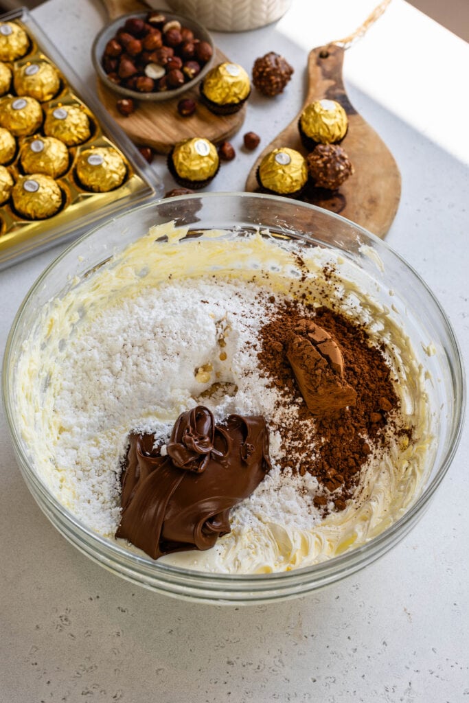ingredients to make nutella buttercream: powdered sugar, vanilla, nutella, heavy cream, and butter.