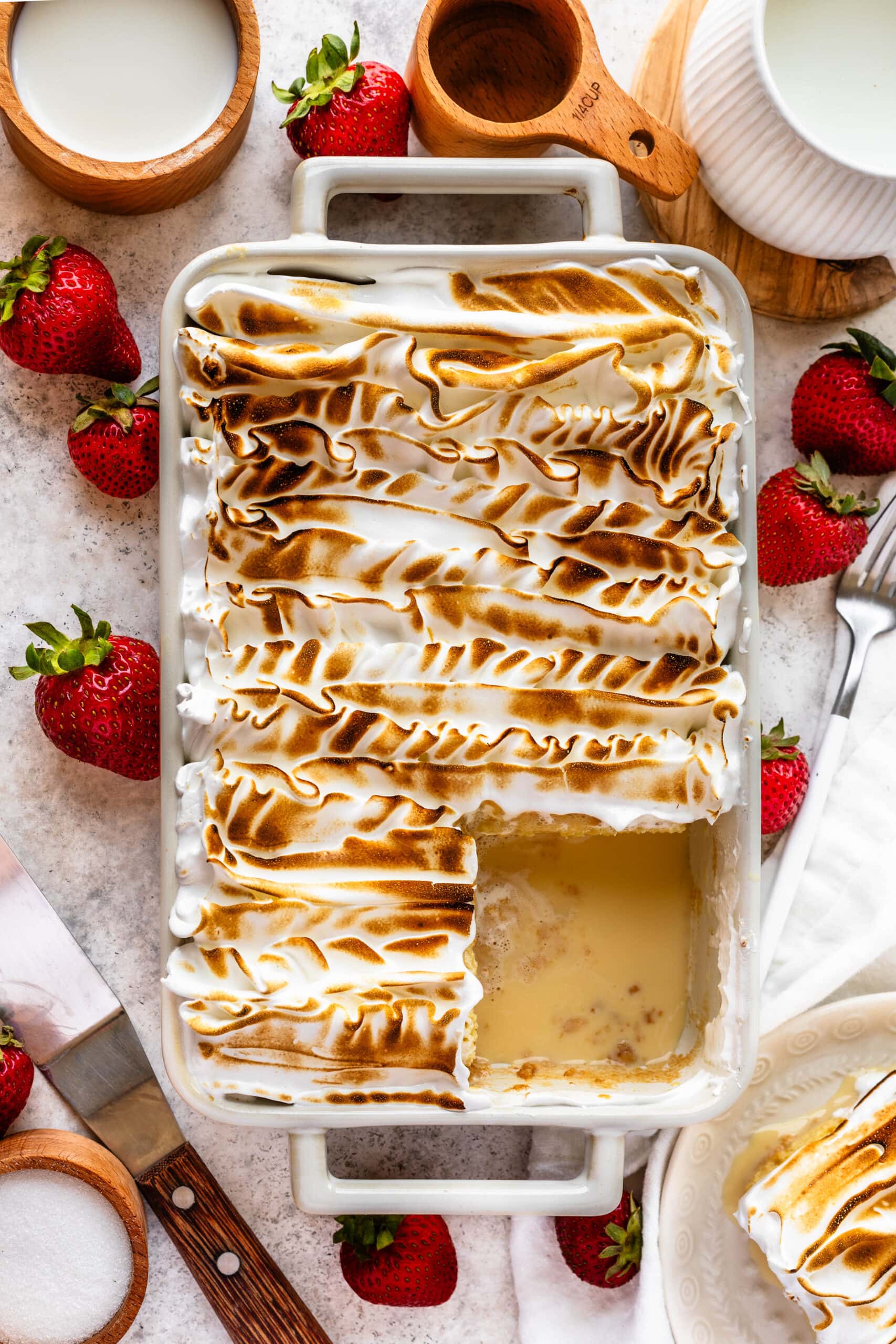 tres leches cake with toasted meringue on top and one slice cut out.