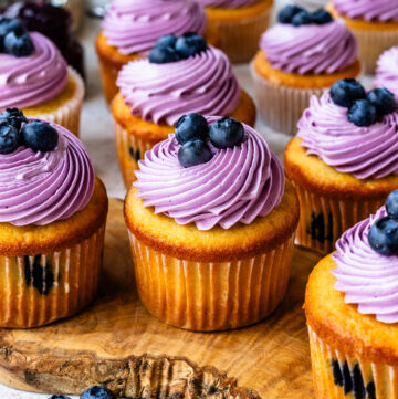 Blueberry cupcakes topped with blueberry frosting and blueberries.