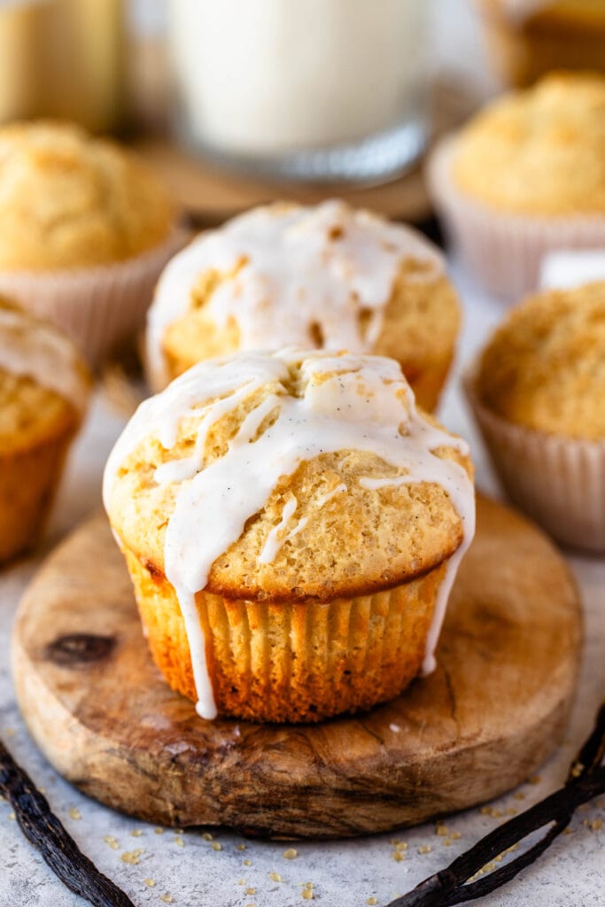 Vanilla muffins with vanilla glaze on top on a wooden board.