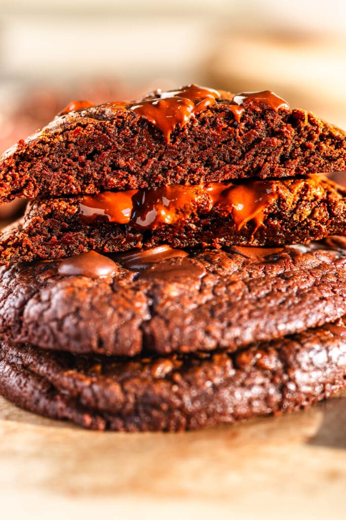 Brownie Cookies sliced in half on top of another cookie with chocolate around.