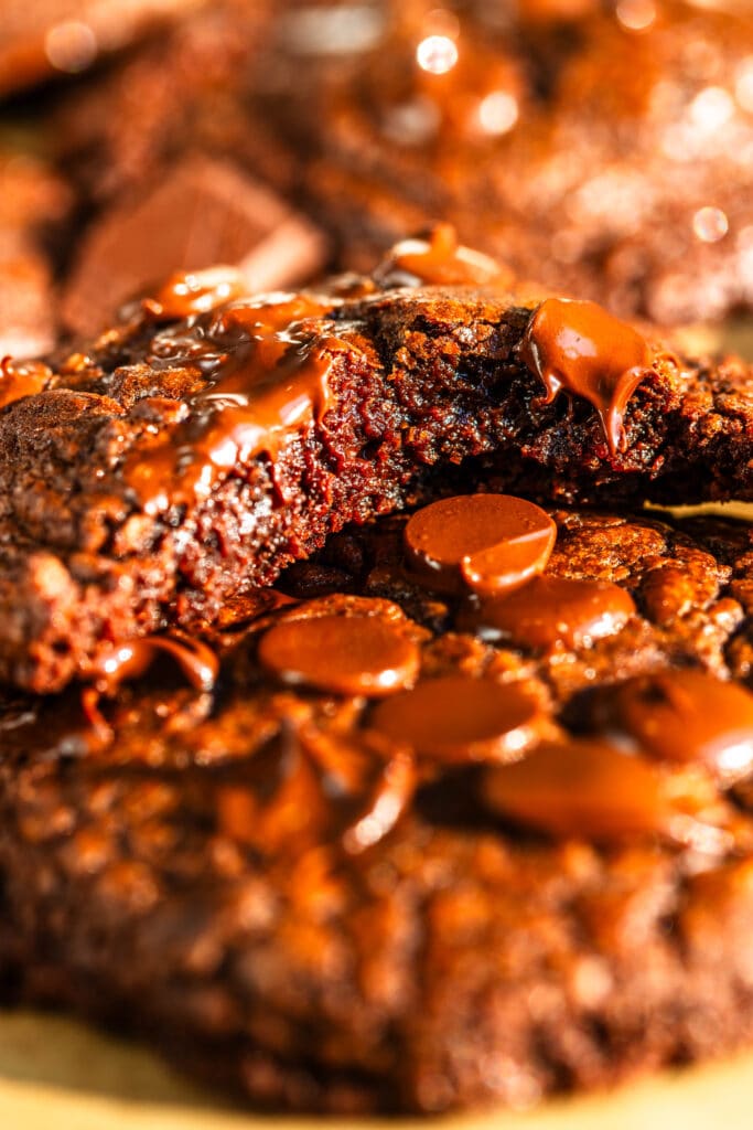 Brownie Cookies sliced in half on top of another cookie with chocolate around.