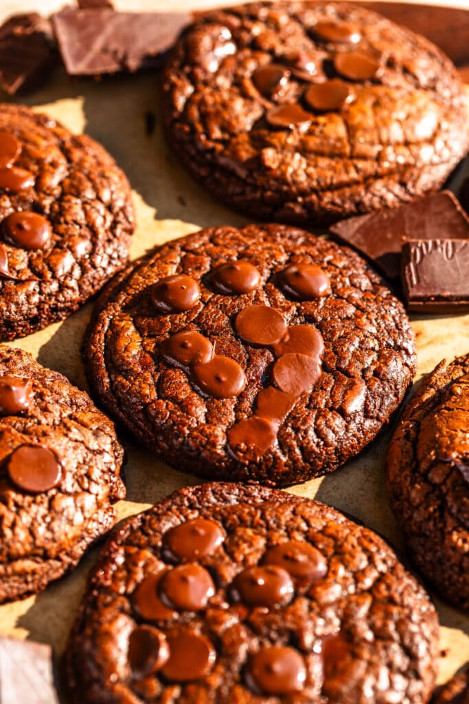 Brownie Cookies sliced in half on top of another cookie with chocolate around.