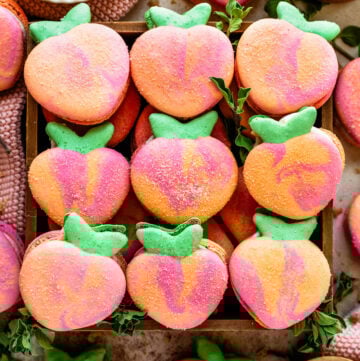 Macarons shaped like peaches in a box.