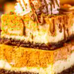 Two pumpkin cheesecake bars stacked on top of each other, with whipped cream and biscoff drizzle on top.