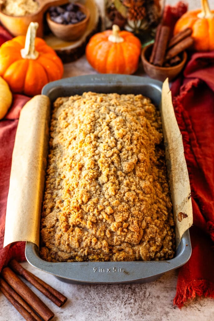 pumpkin bread recipe baked in a loaf pan with pumpkins on the back.