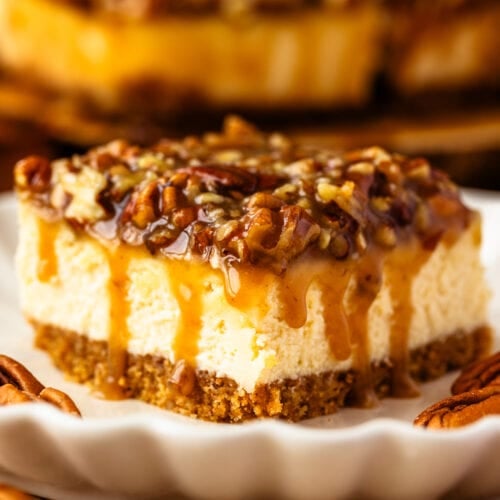 slice of pecan pie cheesecake bar with caramel pecan on top.