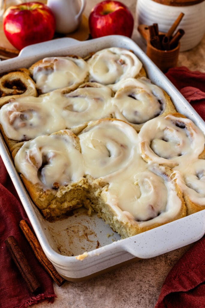 apple pie cinnamon rolls in a 9x13" tray, with glaze on top.