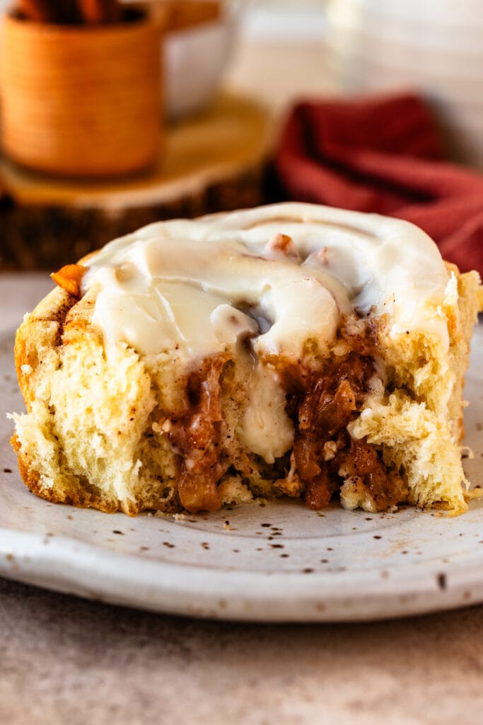 Apple Pie Cinnamon Roll on a plate, cut in half.