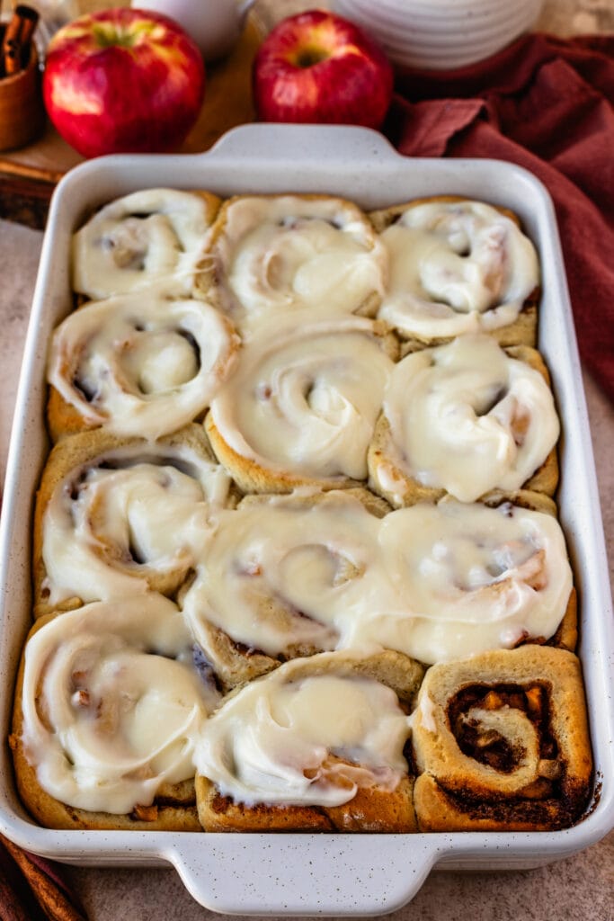 apple pie cinnamon rolls in a 9x13" tray, with glaze on top.