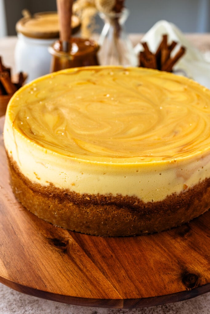 dulce de leche cheesecake with graham cracker crust, on top of a wooden board.
