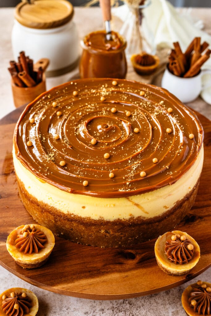 cheesecake with dulce de leche on top, and crispearls, on a wooden board.