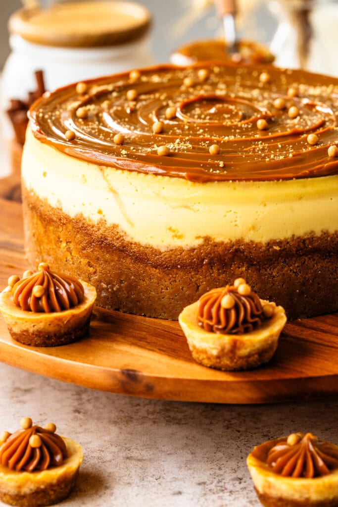 cheesecake with dulce de leche on top, and crispearls, on a wooden board.