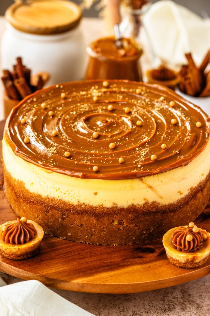 cheesecake with dulce de leche on top, and crispearls, on a wooden board.