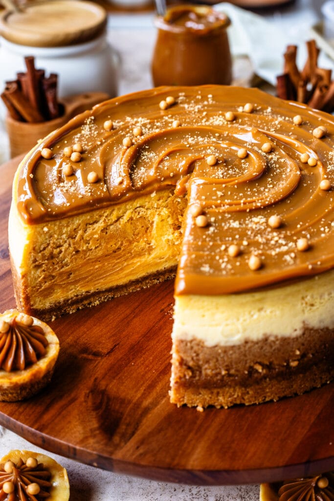 cheesecake with dulce de leche on top, and crispearls, on a wooden board.