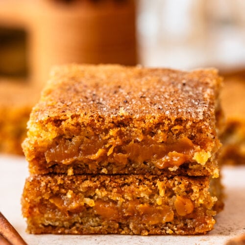 snickerdoodle bars filled with dulce de leche stacked on top of each other.