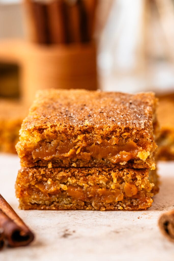 snickerdoodle bars filled with dulce de leche stacked on top of each other.