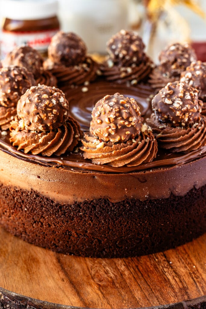 Nutella hazelnut cheesecake with ferrero rocher on top and chocolate whipped cream.