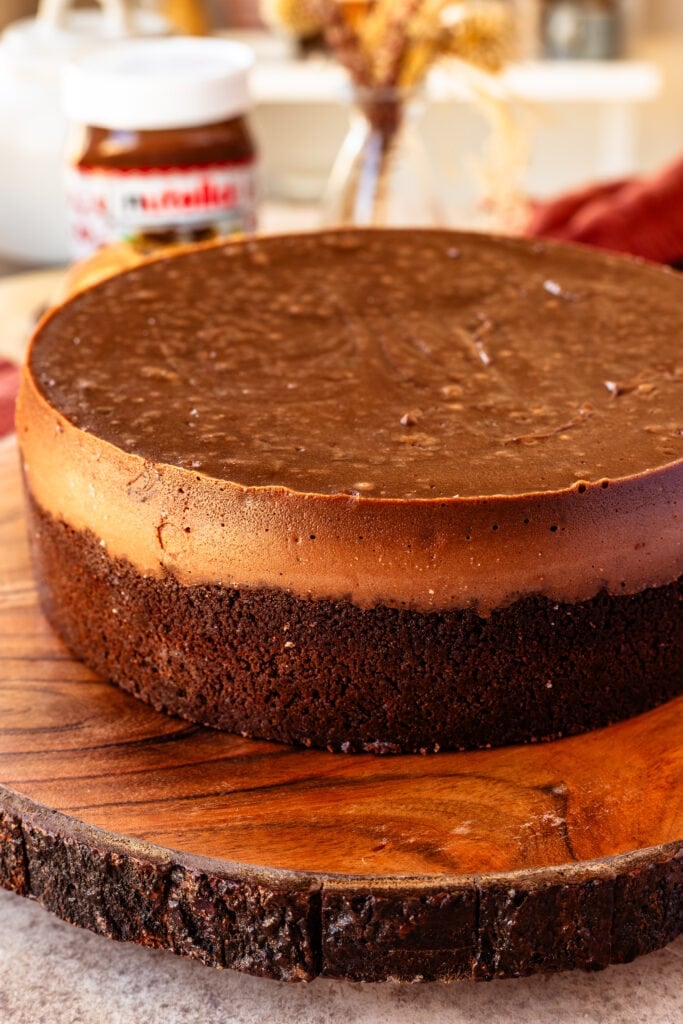 nutella cheesecake with chocolate cookie crust on top of a wooden board.