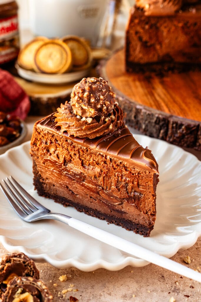 Nutella chocolate cheesecake slice with swirls of nutella, a ferrero rocher on top.