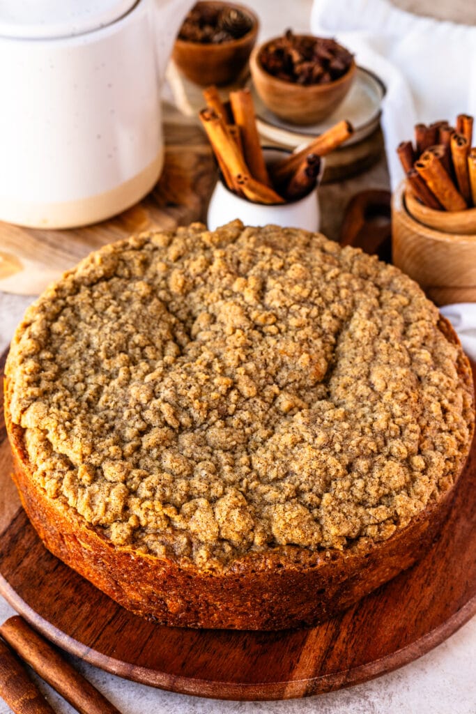 cake with crumb on top, cinnamon sticks in containers around.