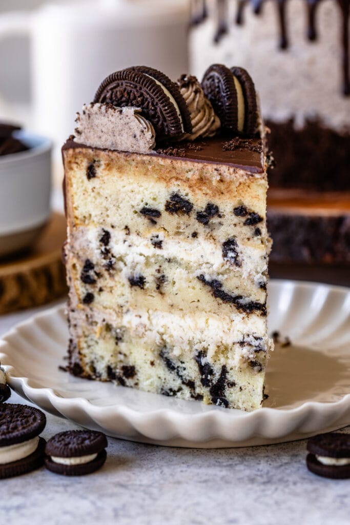 slice of cookies and cream cake, with mousse filling, topped with a ganache drip and oreo cookies.