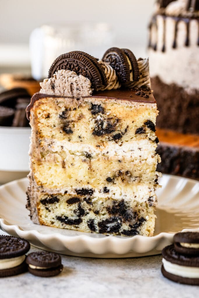 slice of cookies and cream cake, with mousse filling, topped with a ganache drip and oreo cookies.