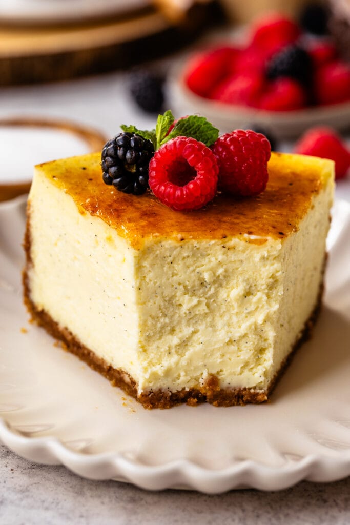 slice of creme brulee cheesecake on top of a plate, with berries on top.