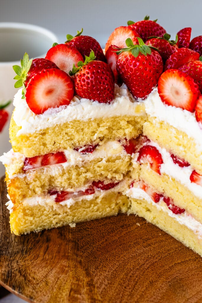 strawberry cake with whipped cream and fresh strawberries, sliced in half.