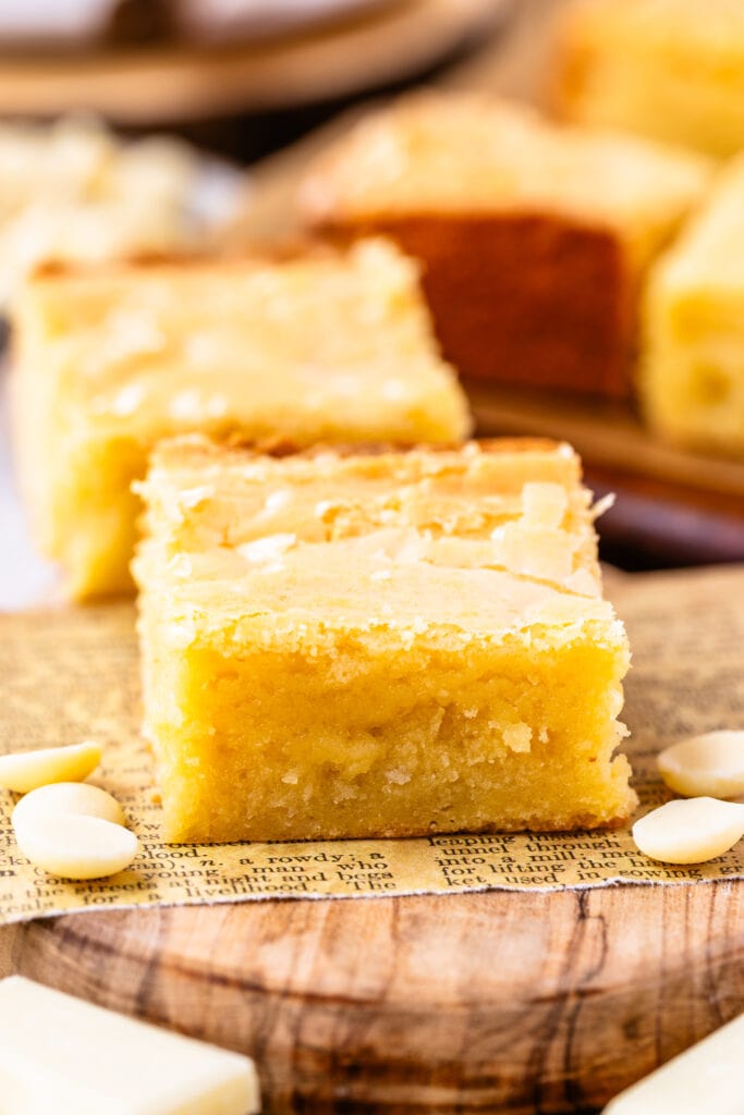 slice of white chocolate brownie on top of a wooden board.