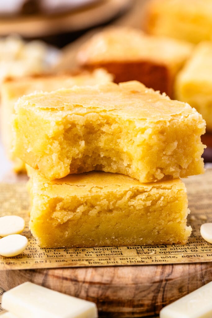 two pieces of white brownies stacked on top of each other on a wooden board.