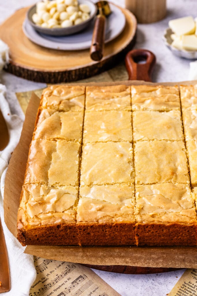 white chocolate brownies sliced into squares on top of a wooden board.