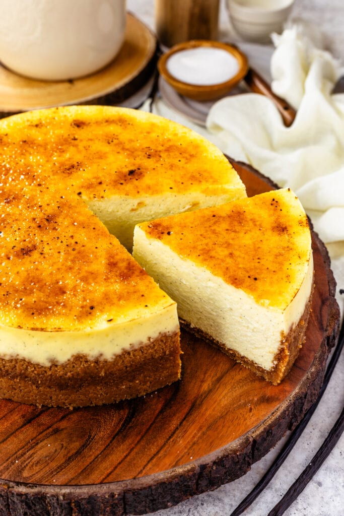 Crème Brûlée Cheesecake sliced on top of a wooden board.