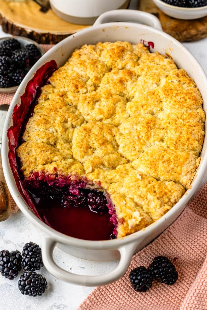 blackberry cobbler in a dish with a piece of it taken out.
