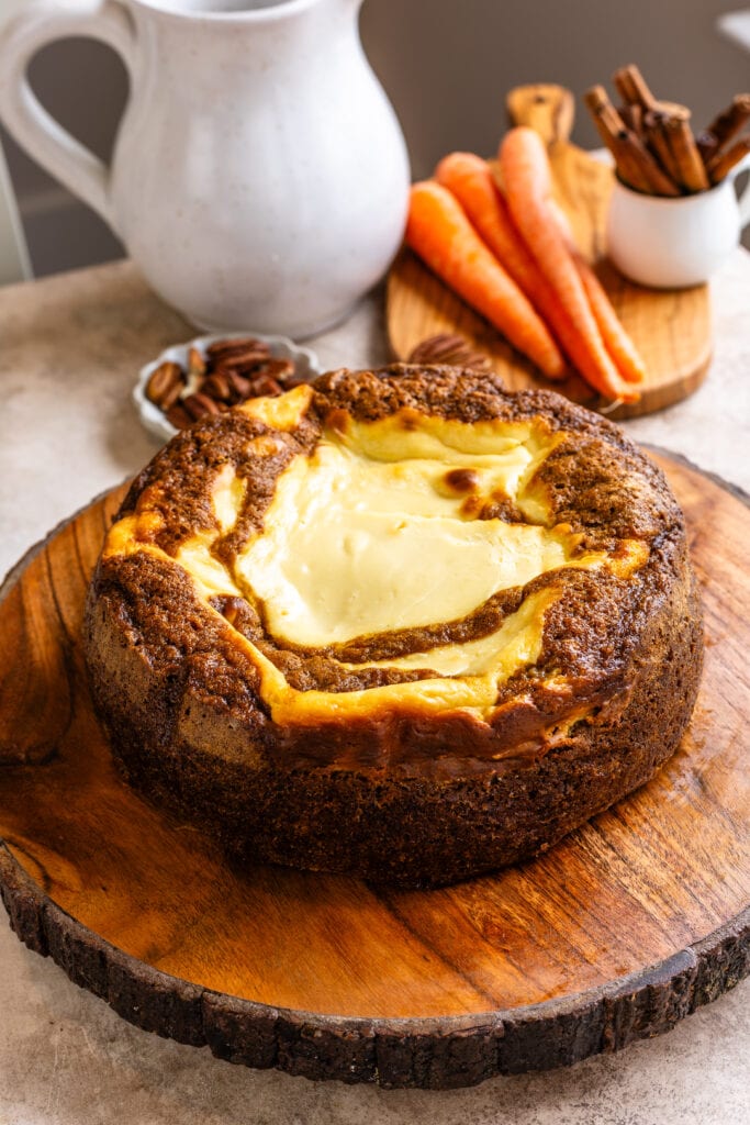 carrot cake baked cheesecake on top of a wooden board.