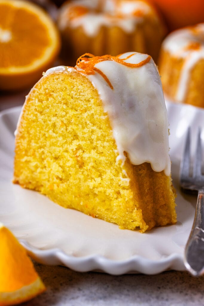 slice of orange cake with glaze on top and orange zest.