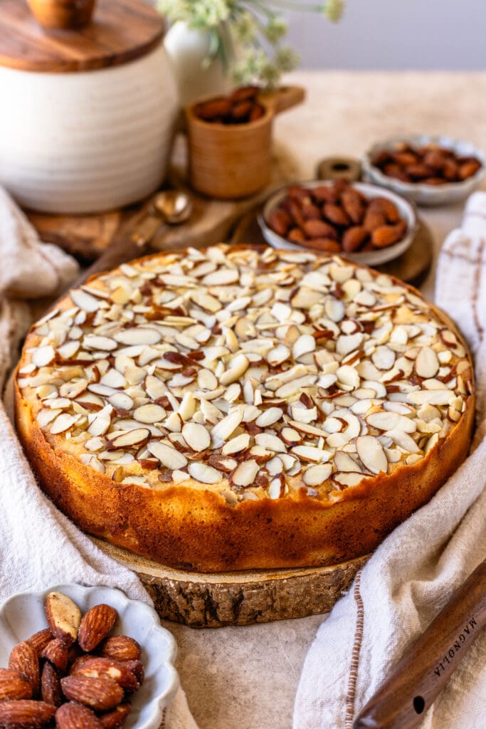 almond cake with almonds and powdered sugar on top, and the cake is on top of a wooden board.