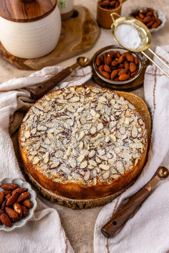 almond cake with almonds and powdered sugar on top, and the cake is on top of a wooden board.