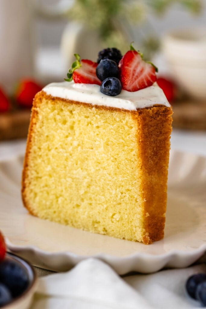 slice of cream cheese pound cake on a plate with glaze on top.